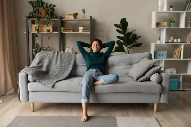 Happy woman relaxing on a clean sofa after completing household cleaning